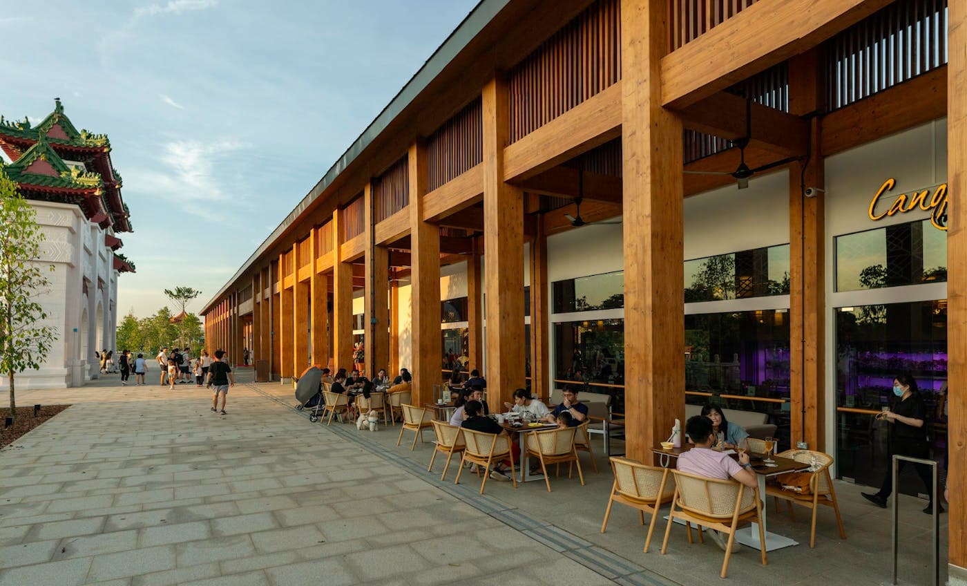 Guests at outdoor tables along the timber colonnade at dusk