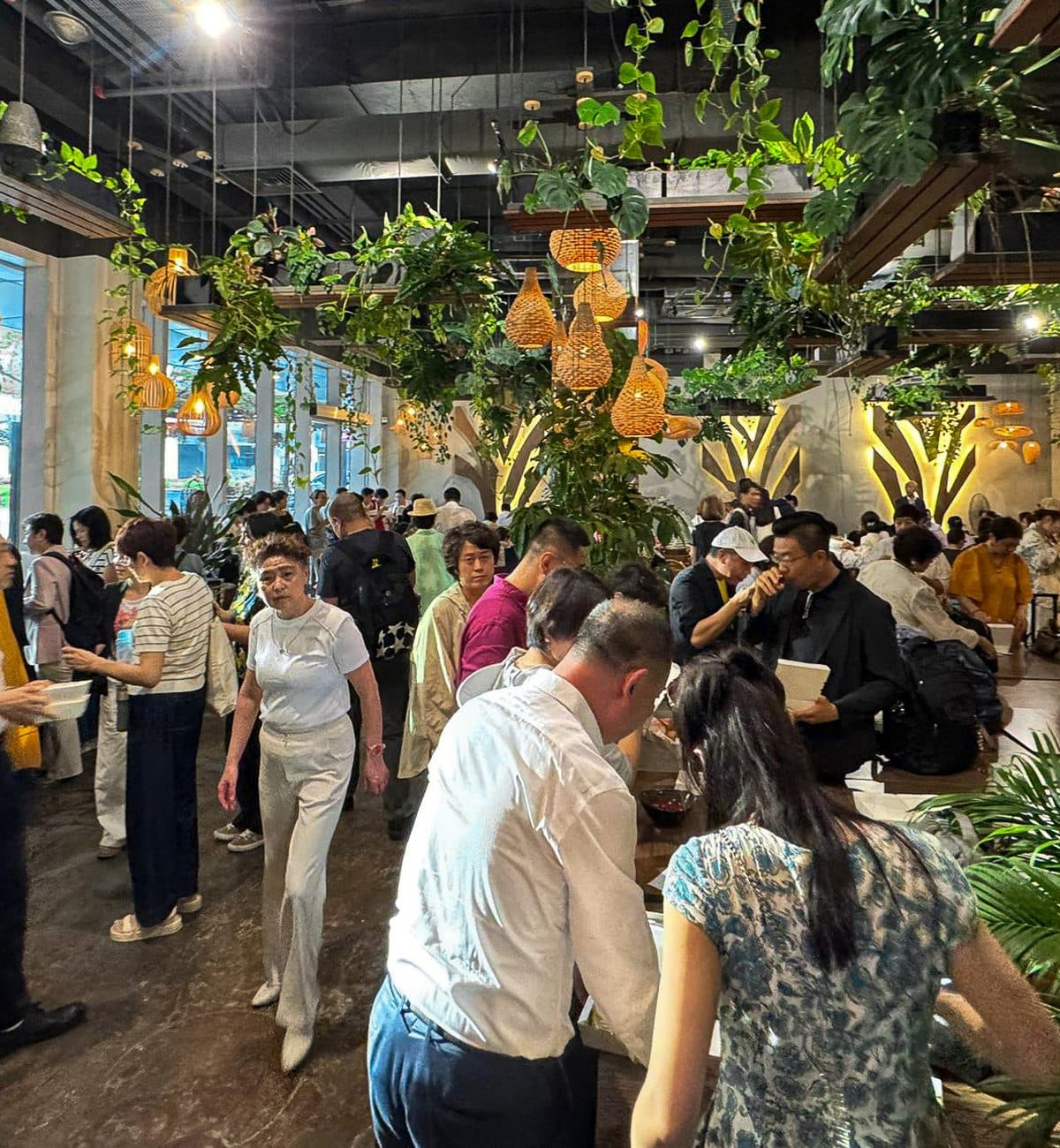 A full room at Canopy Changi City Point during a company event, hanging plants overhead