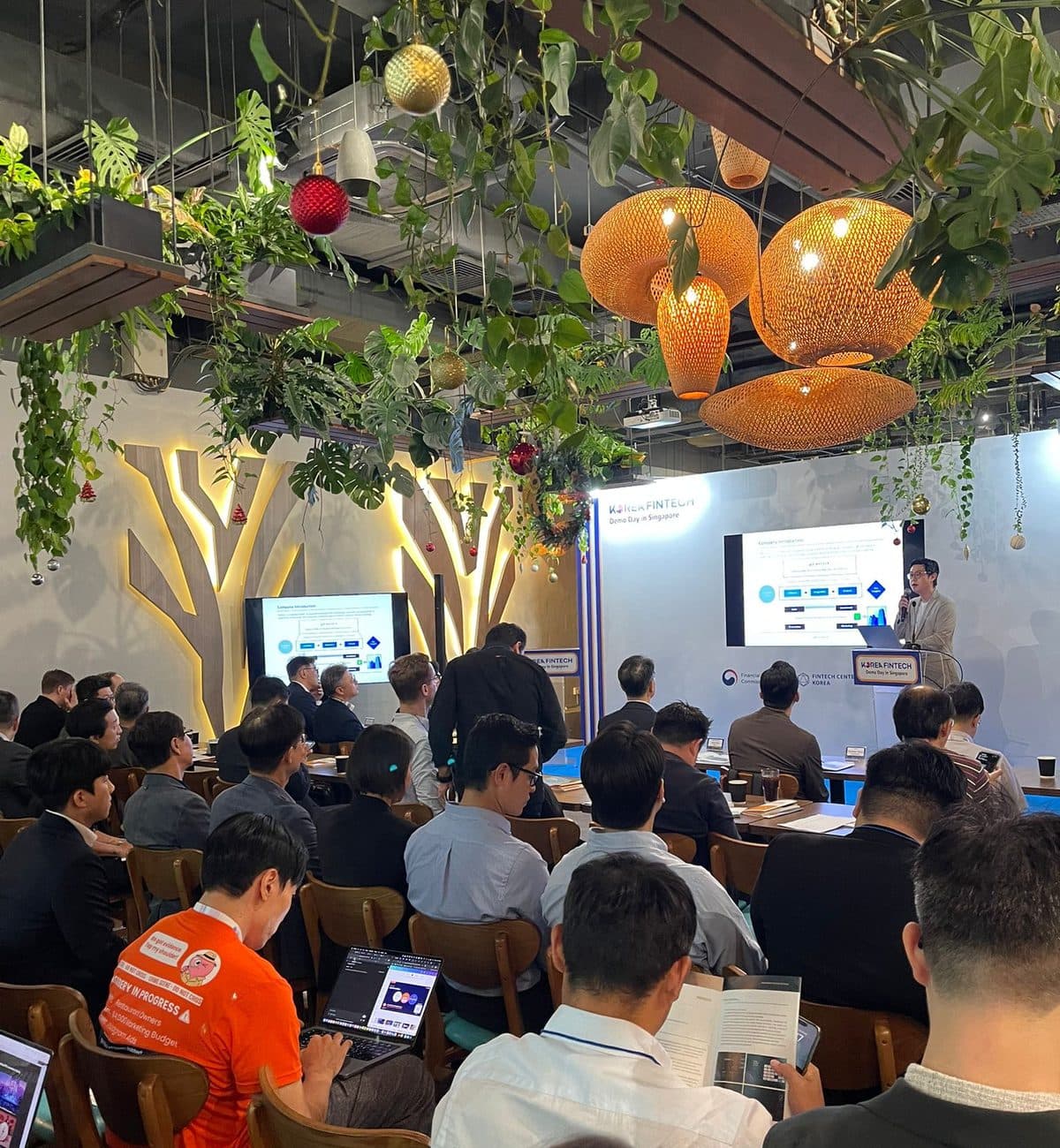 A packed presentation at Canopy Changi City Point, guests at long tables facing the screens