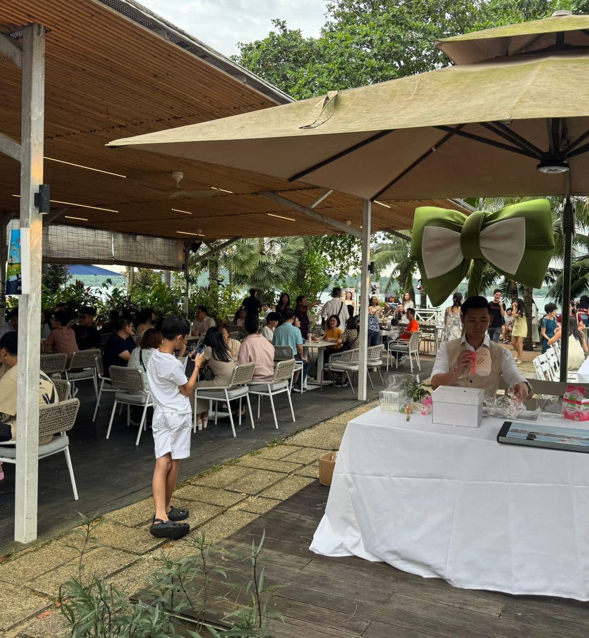 An outdoor company event under parasols at Canopy Changi Village, a welcome table at the front