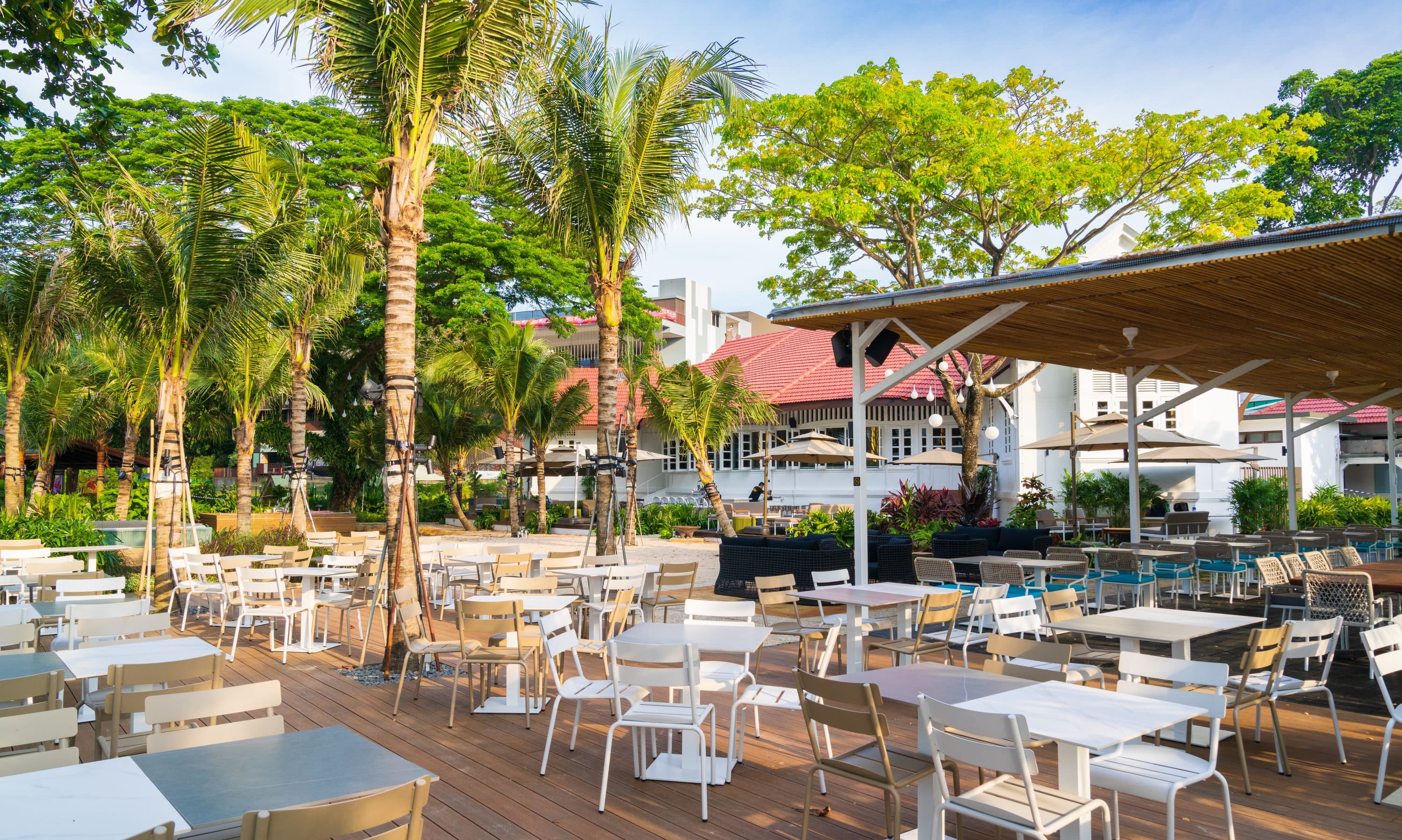 The timber deck at Canopy Changi Village set with white tables under the palms