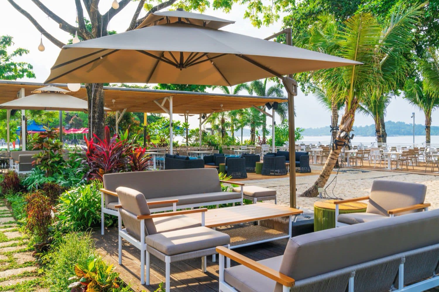 Lounge seating under a parasol at Canopy Changi Village, planting one side and the sand the other
