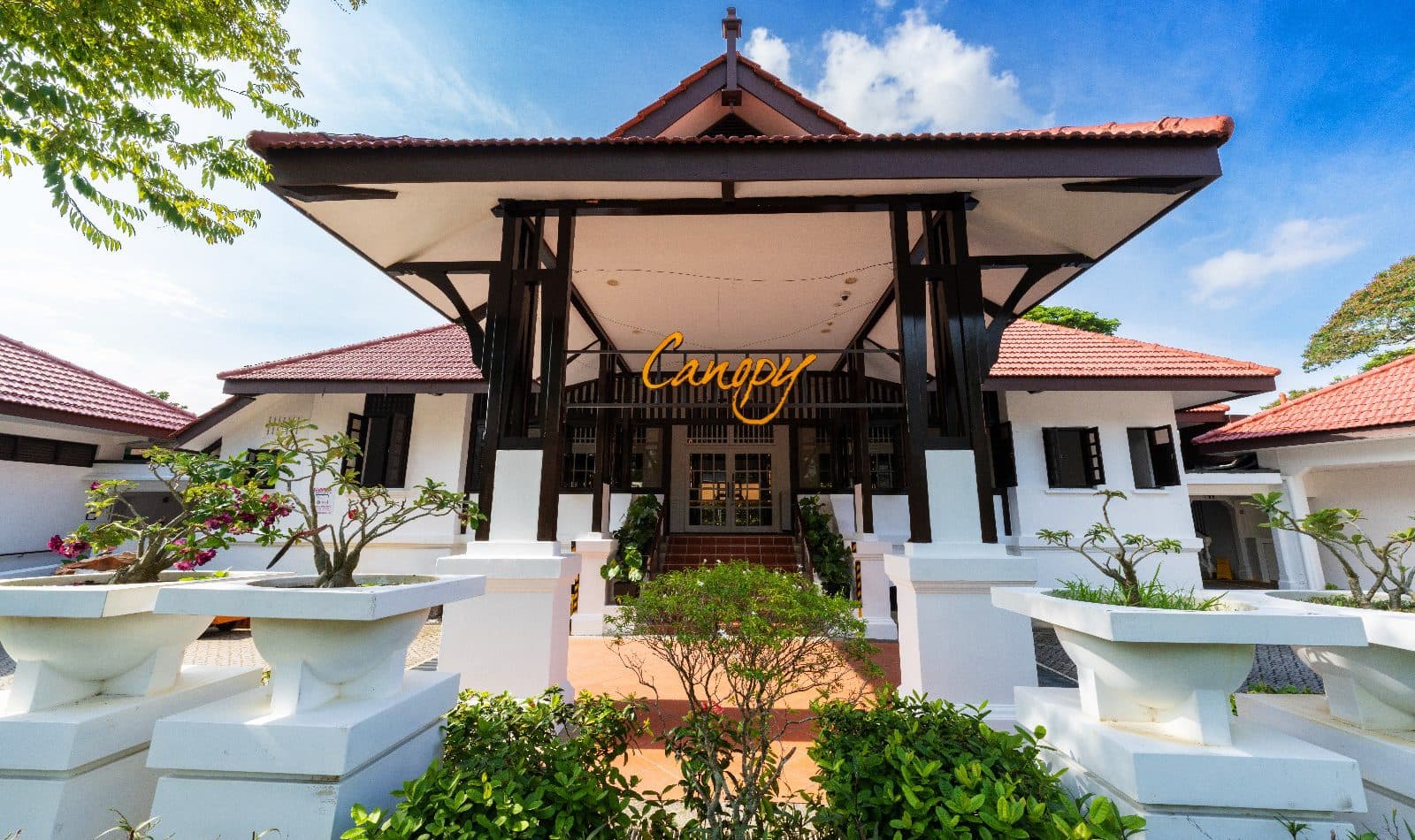 The colonial pavilion at Canopy Changi Village under a blue sky, the Canopy sign beneath the timber roof
