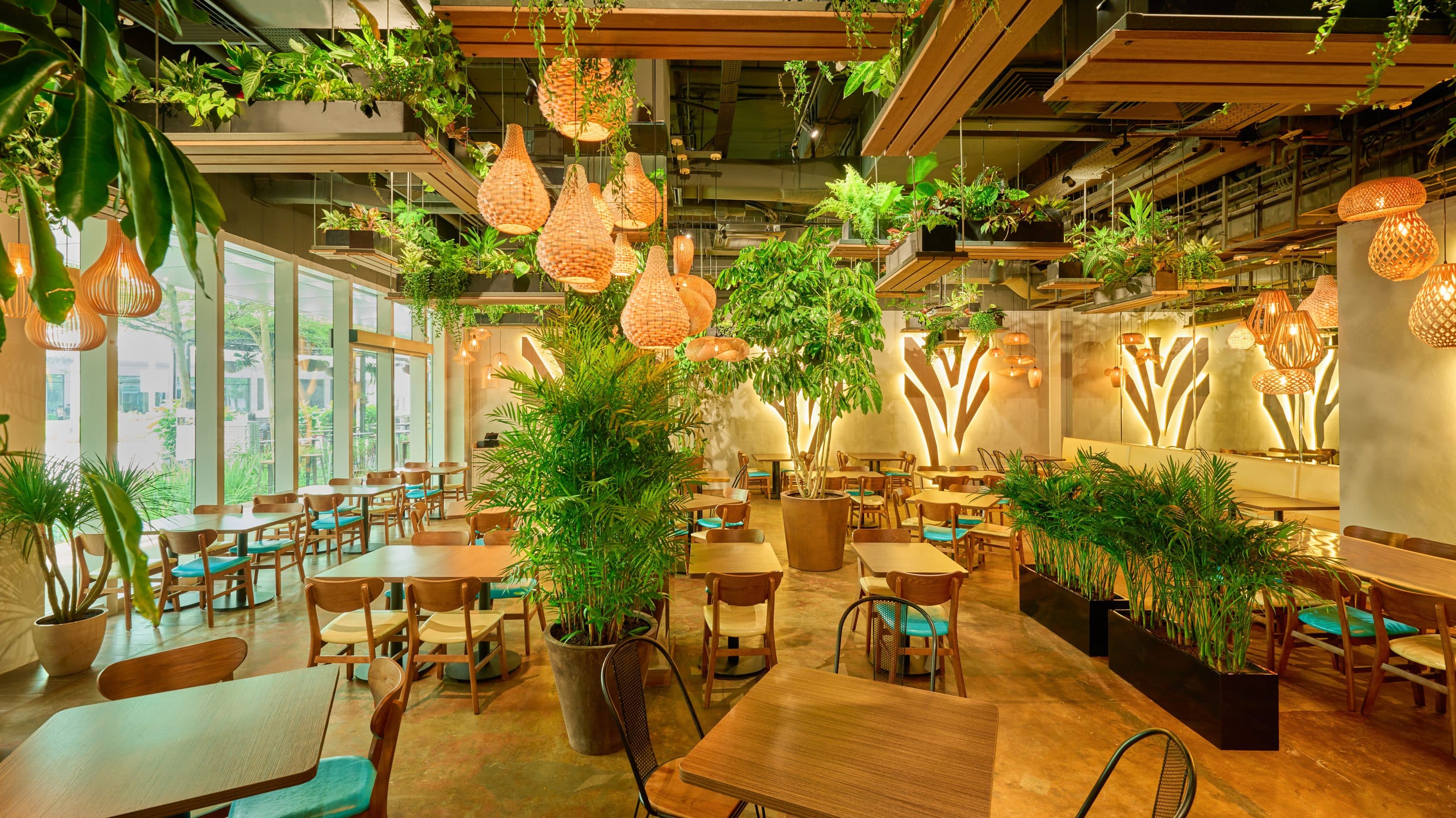 The planted dining room at Canopy Changi City Point under rattan pendants
