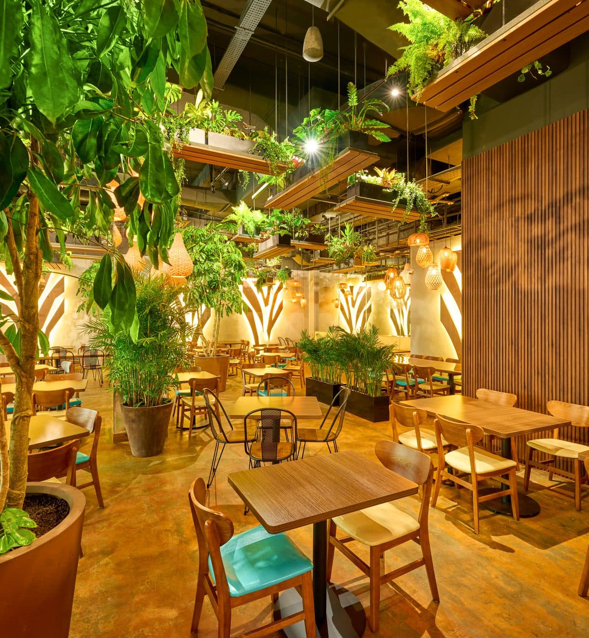 The dining room at Canopy Changi City Point in warm light, planting between the tables