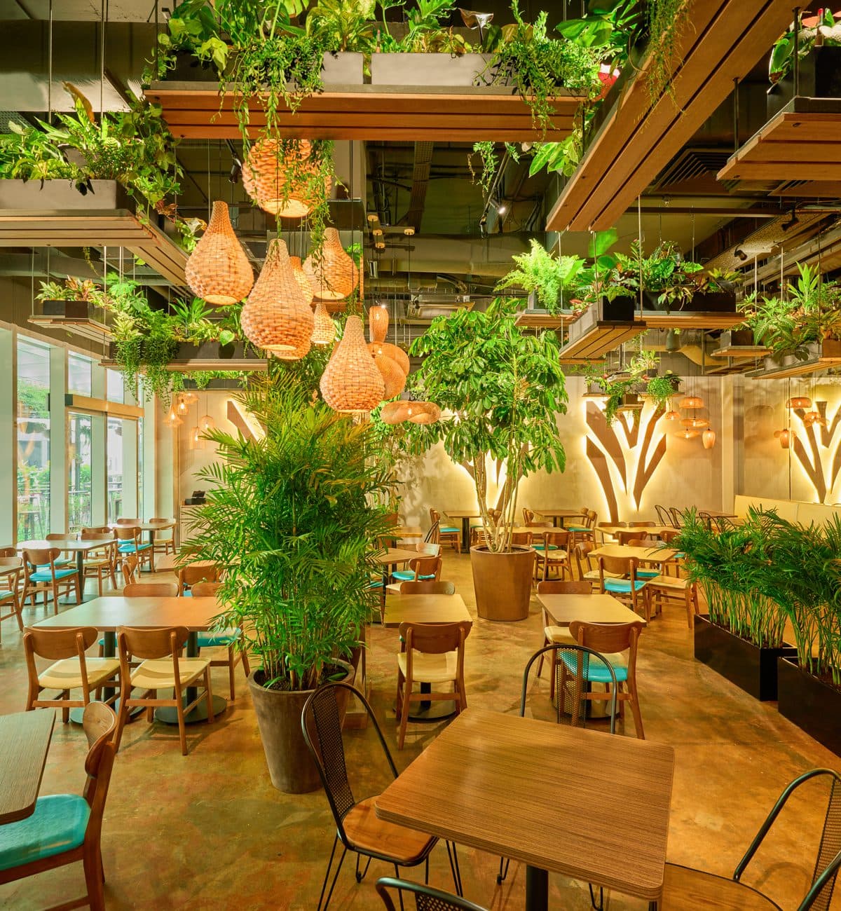 Timber tables and rattan pendants among the planting at Canopy Changi City Point