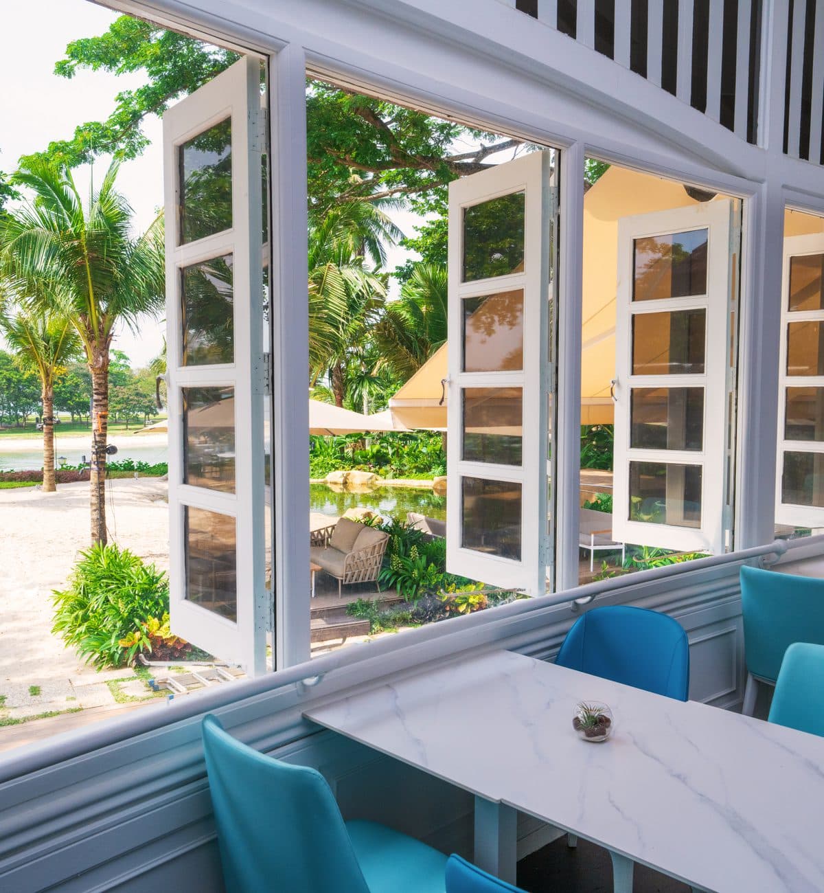 Open colonial doors onto the deck at Canopy Changi Village, palms and the water beyond