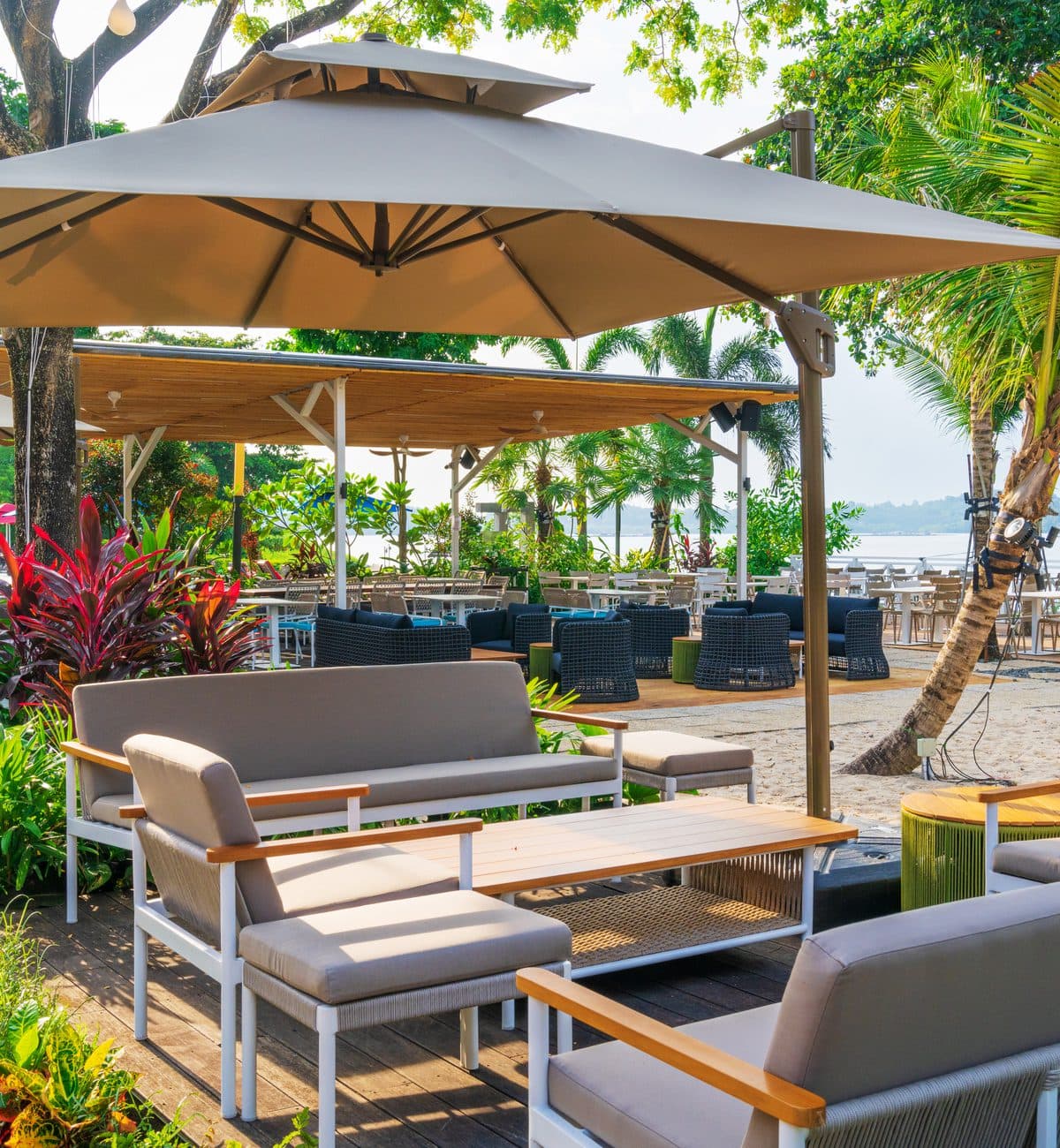 Lounge seating under a parasol at Canopy Changi Village, planting and the water behind