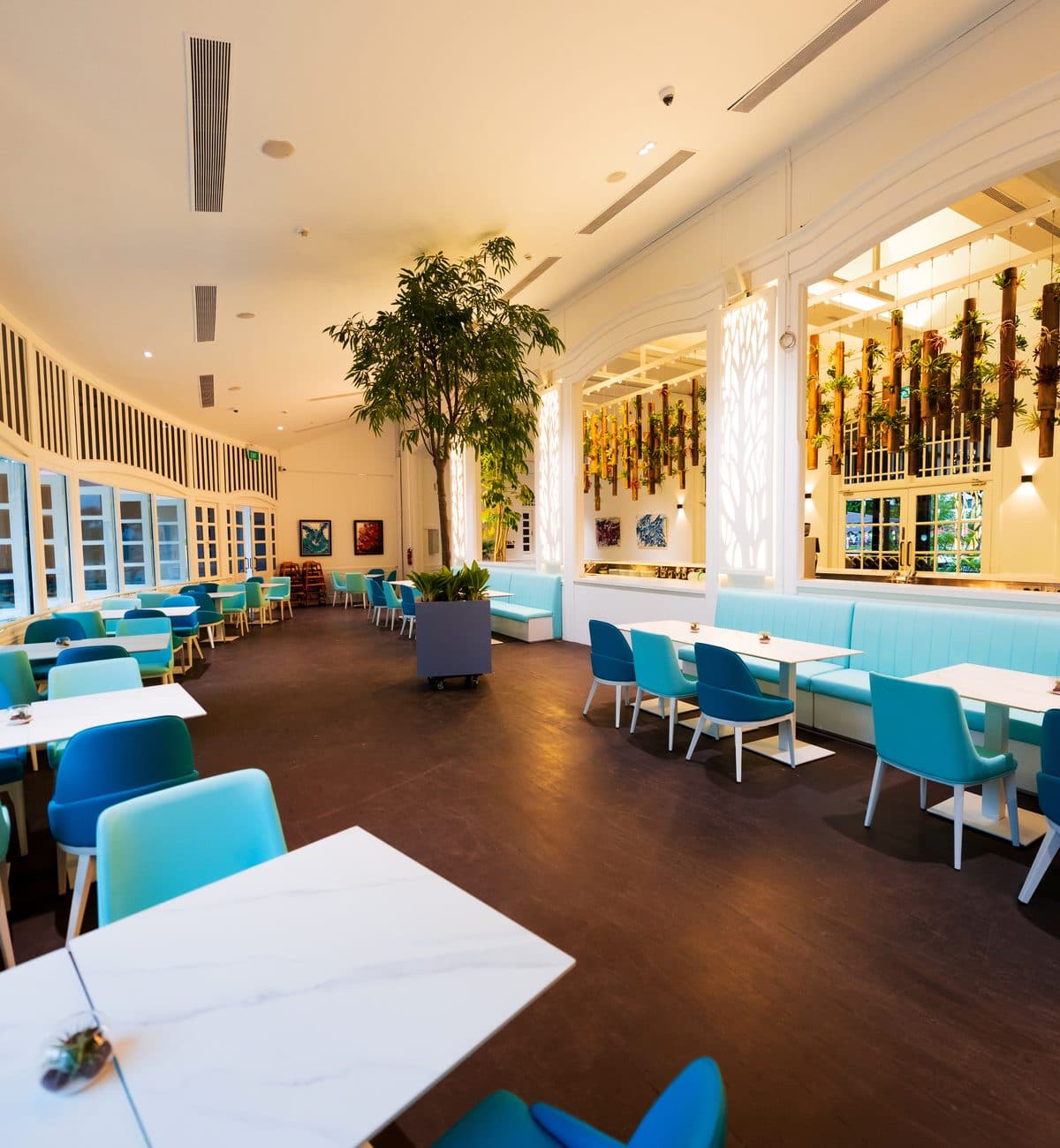 The indoor dining room at Canopy Changi Village, turquoise banquettes along the windows