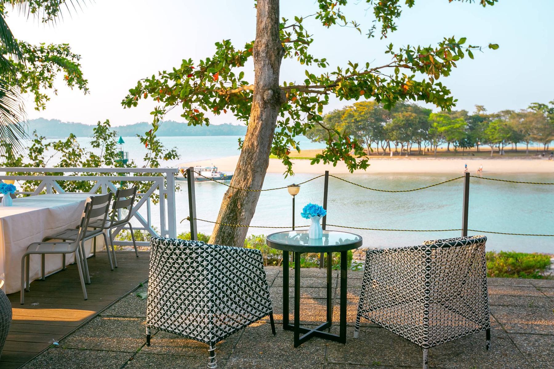 A table for two at the deck's edge at Canopy Changi Village, the sand and the water a step away