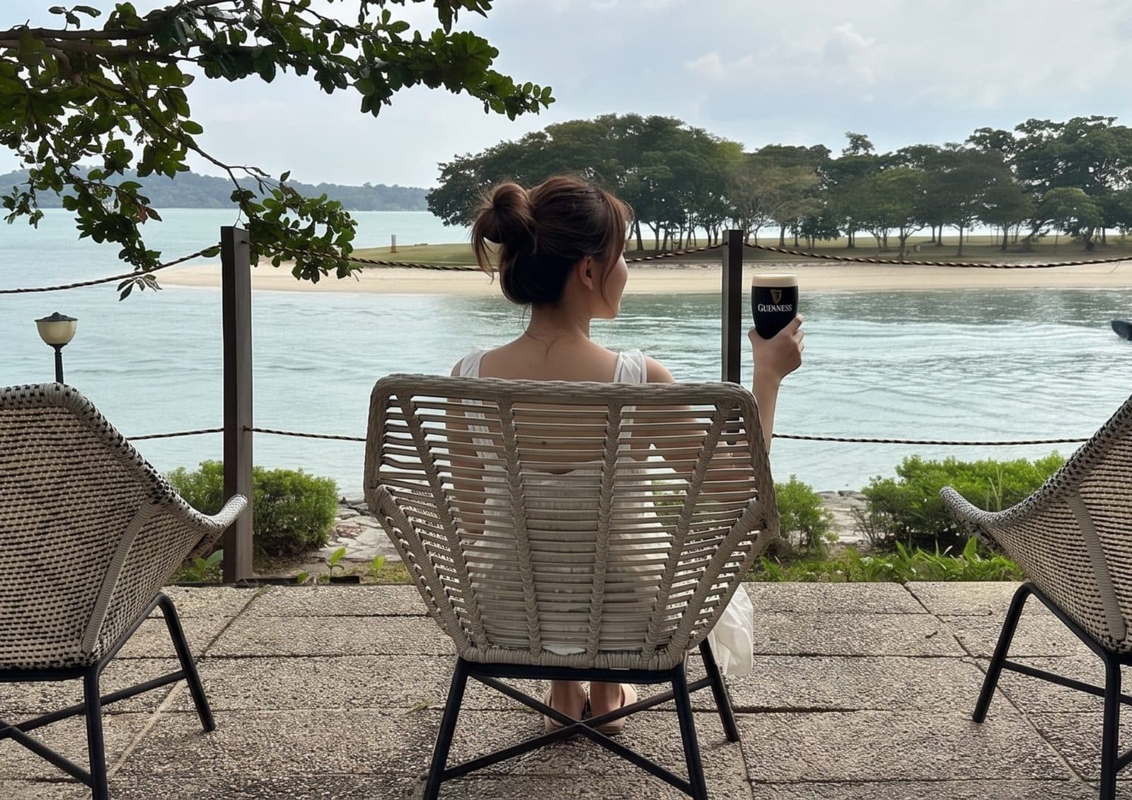 A guest in a rope chair at Canopy Changi Village with a stout, looking out at the sandbar