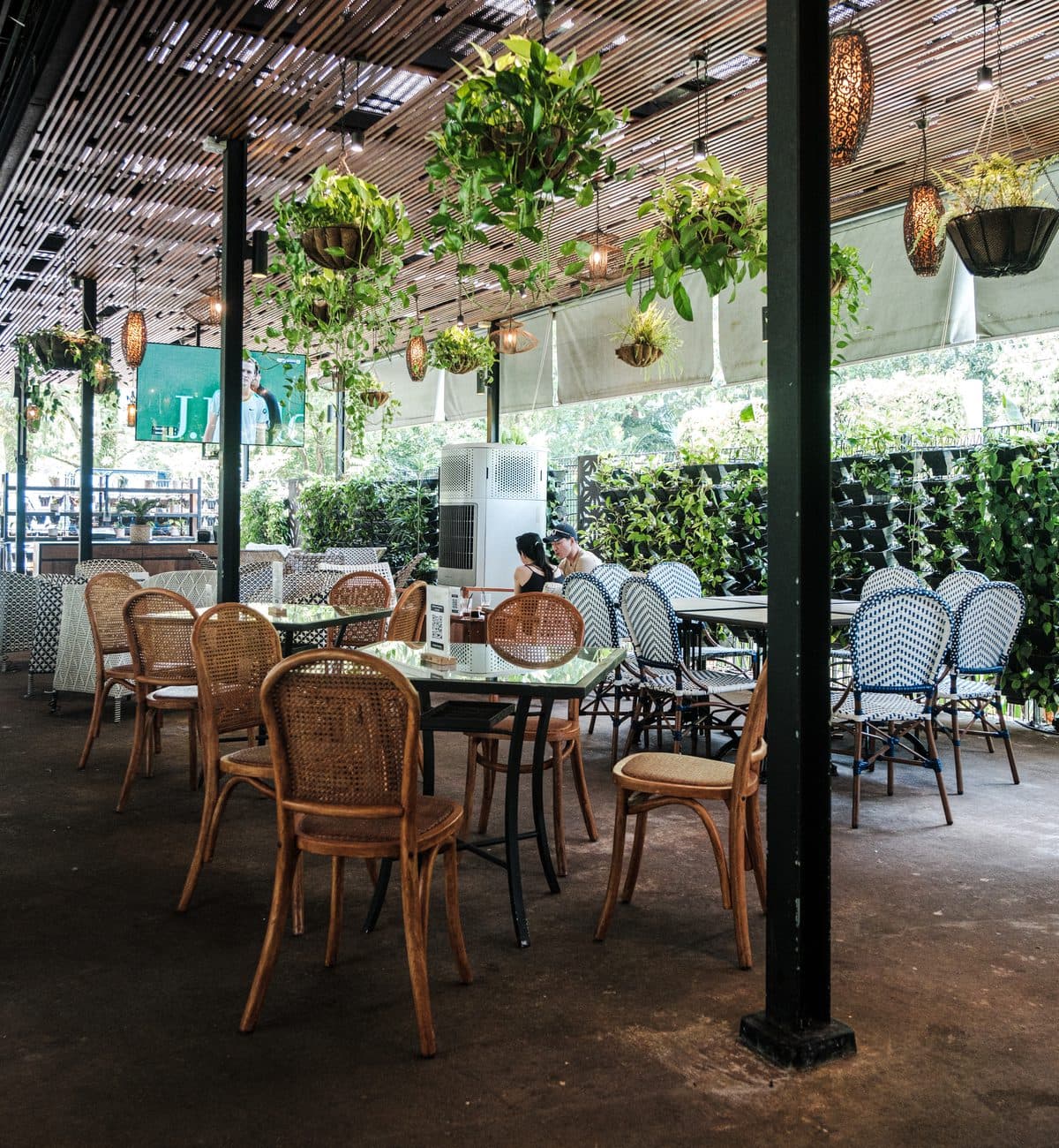 The alfresco area at Canopy HortPark, cane chairs against a green wall