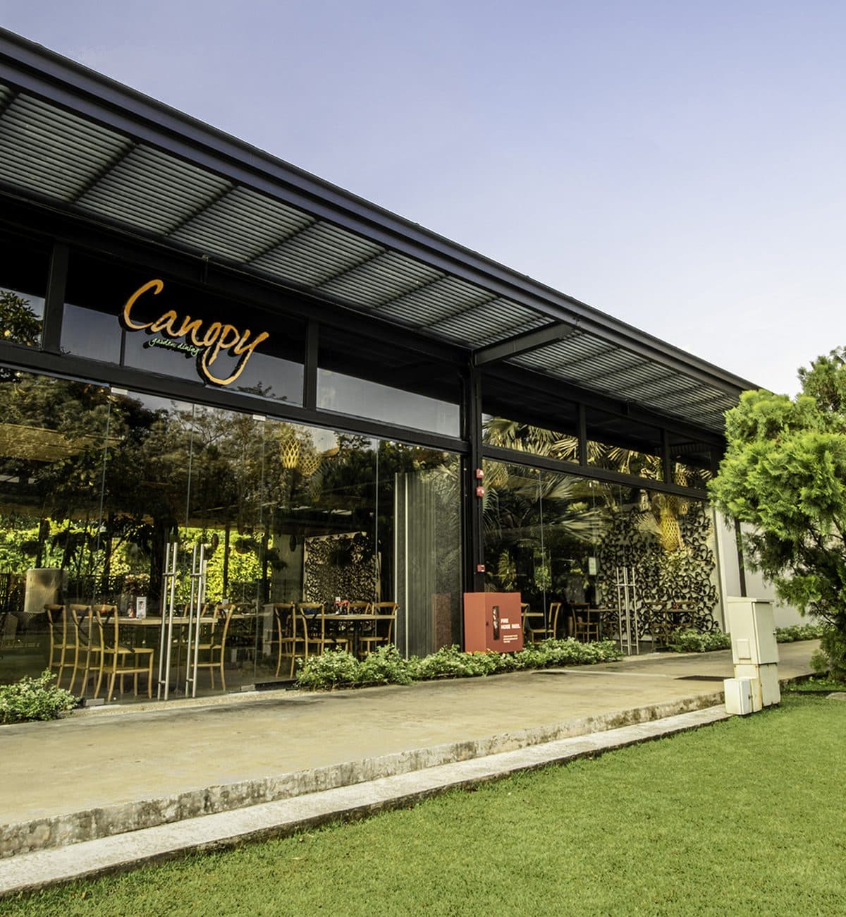 The glass frontage of Canopy HortPark seen across the lawn, the Canopy sign along the roofline