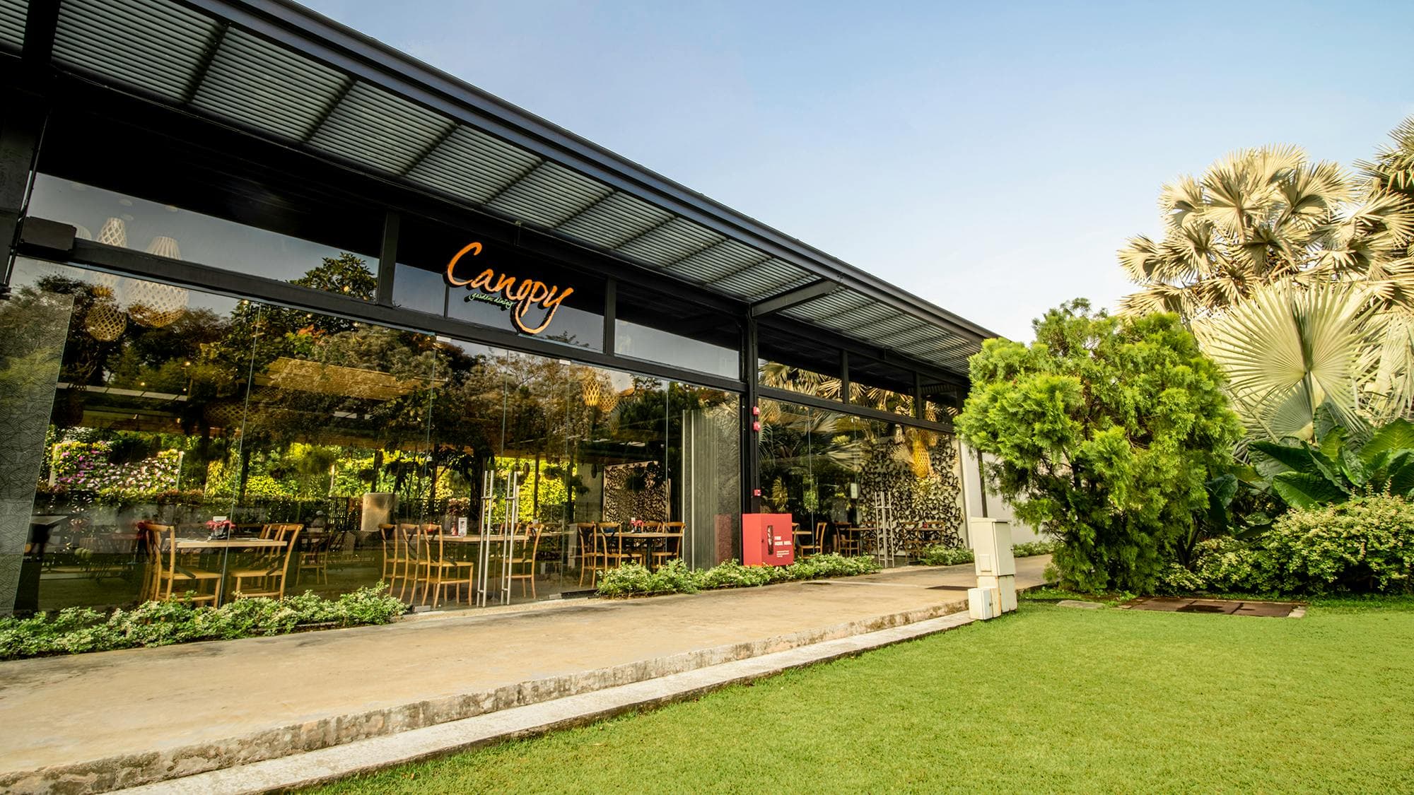The glass-fronted pavilion at Canopy HortPark, opening onto the lawn