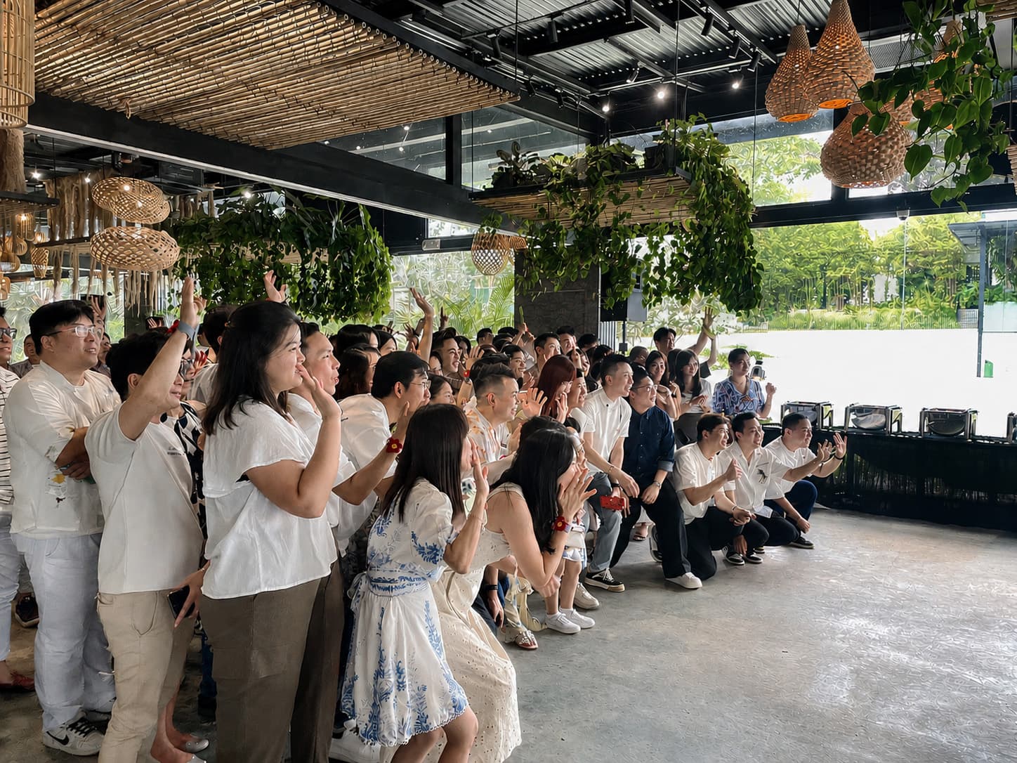 A company group cheering together in the dining room, rattan pendants and hanging planting overhead