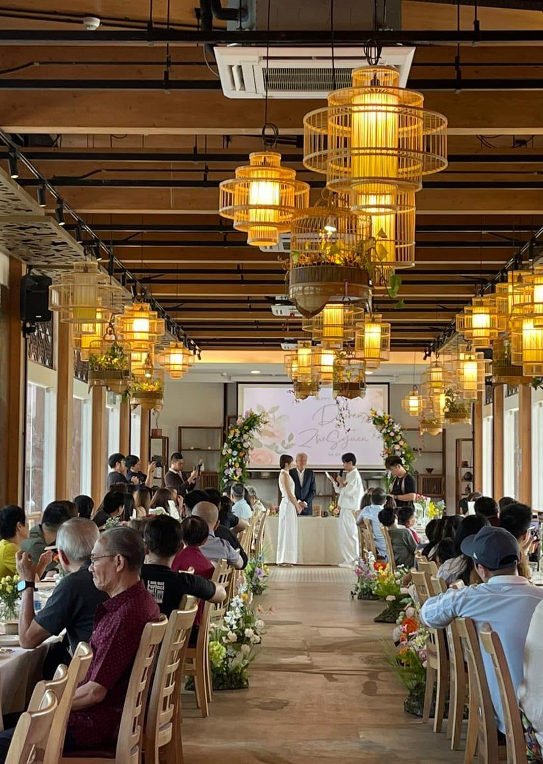 A solemnisation under the timber pavilion at Canopy Jurong Lake Gardens, birdcage lanterns above the guest tables