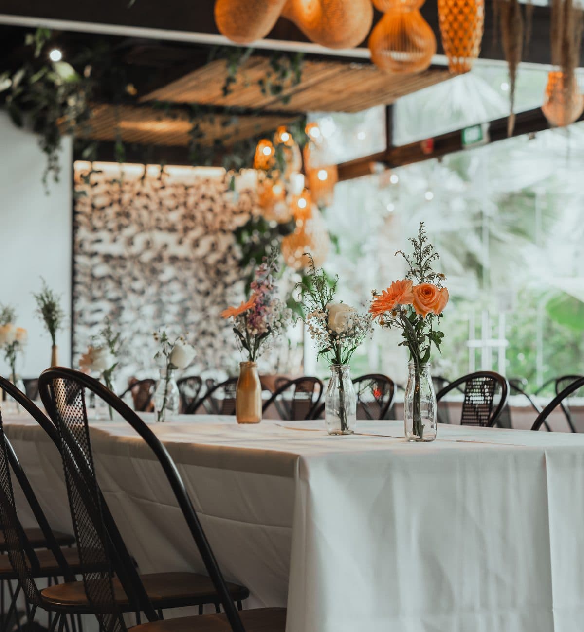 Long tables dressed in white with peach florals at Canopy HortPark