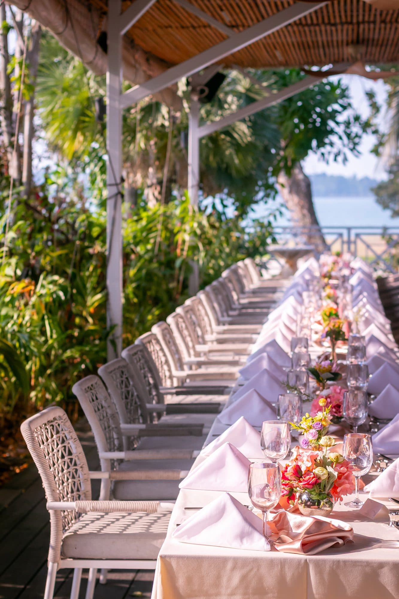 A long table dressed down the deck at Canopy Changi Village, rattan chairs either side and the water at the end