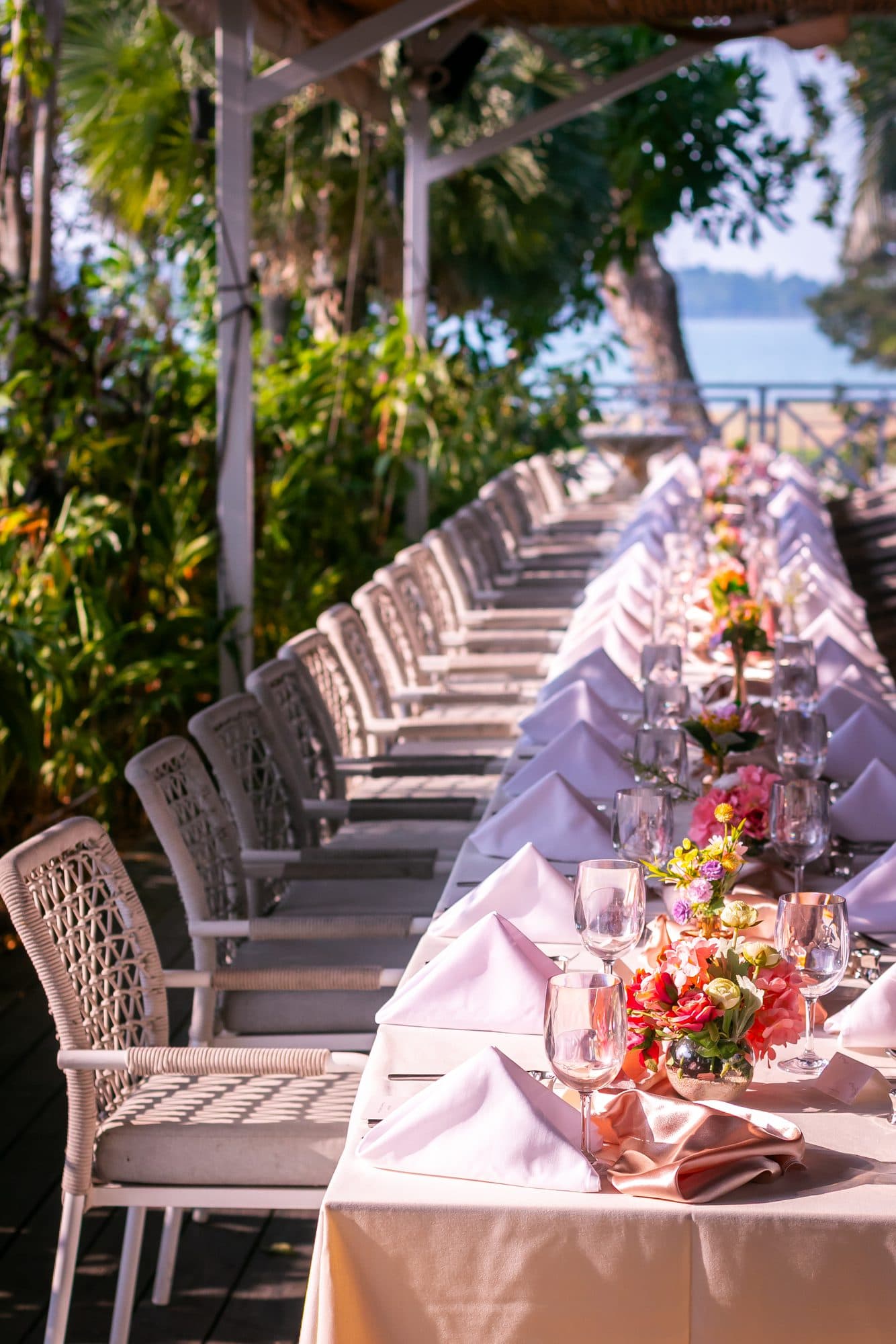 A long banquet table running down the deck at Canopy Changi Village, coral florals along its length