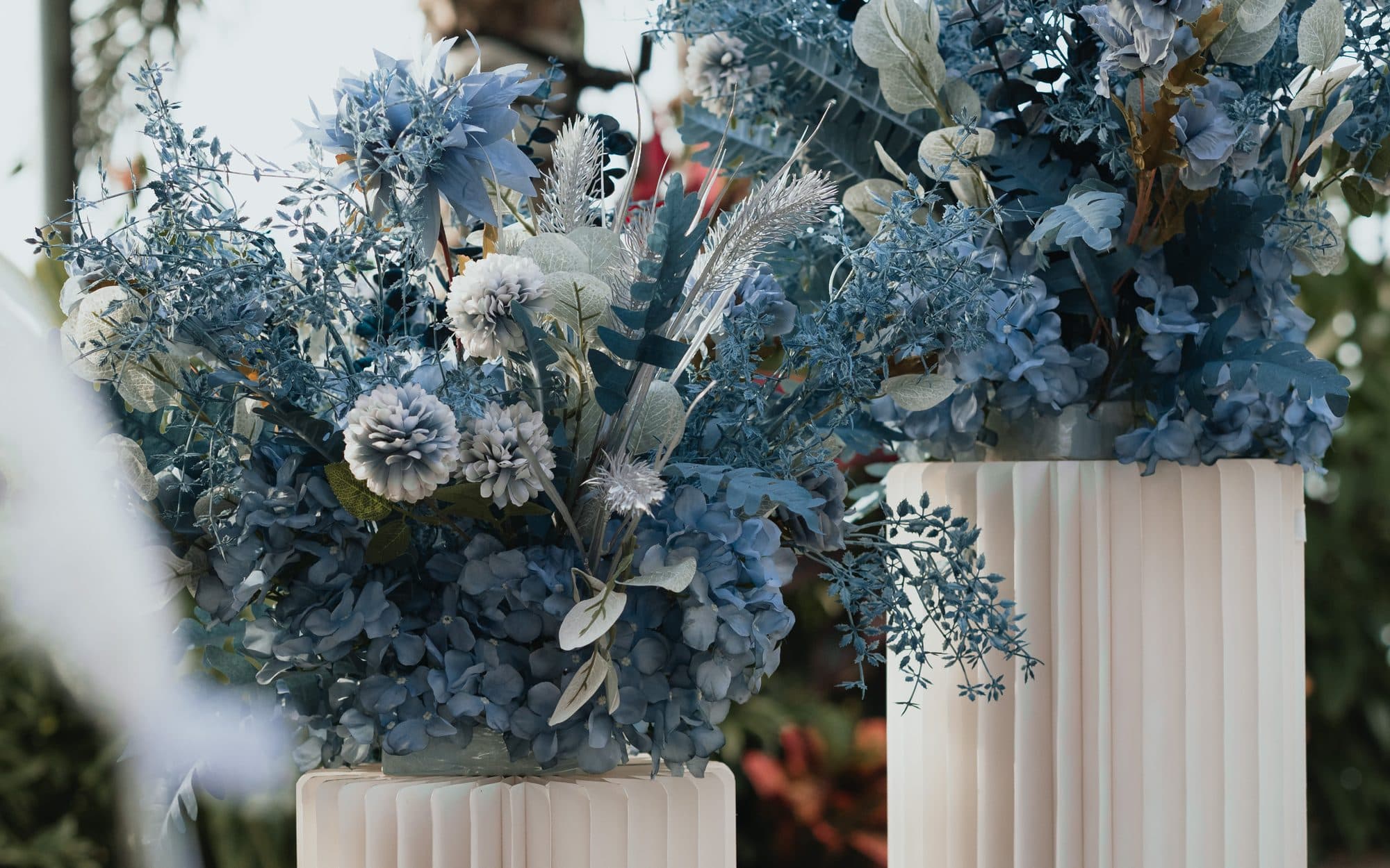 Blue and white florals on fluted plinths at a Canopy Changi Village ceremony