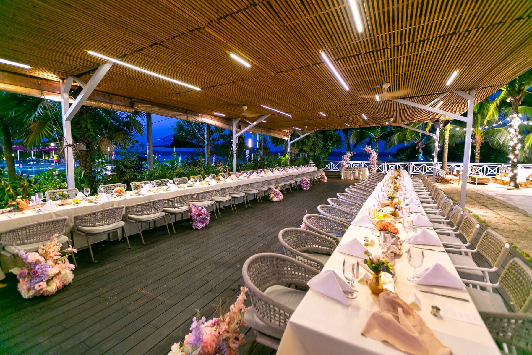 The long tables on the deck at dusk, the lights on overhead