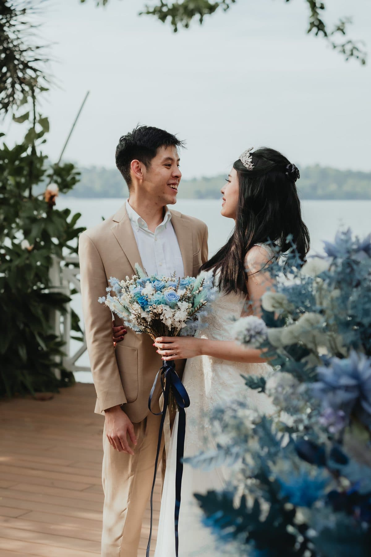 A couple on the timber deck at Canopy Changi Village, blue and white florals with the water behind them